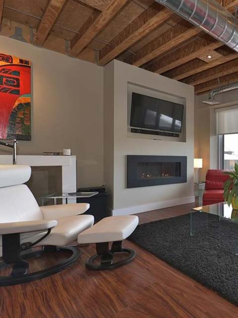 a living room fireplace surrounded by a rug and a white chair