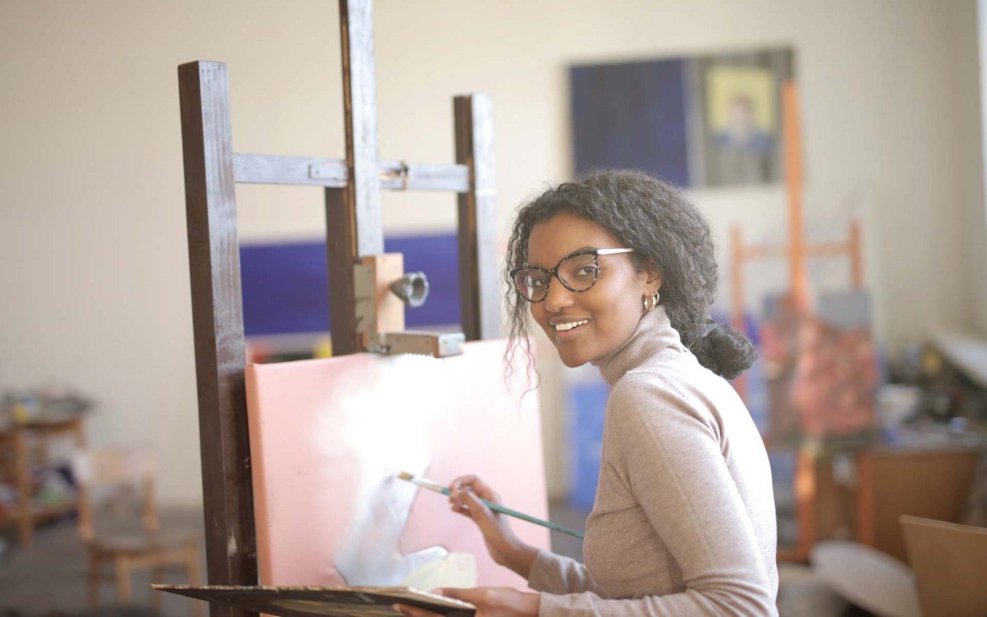 a woman smiling and painting on a canvas