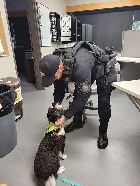 policeman petting a black and white puppy indoors