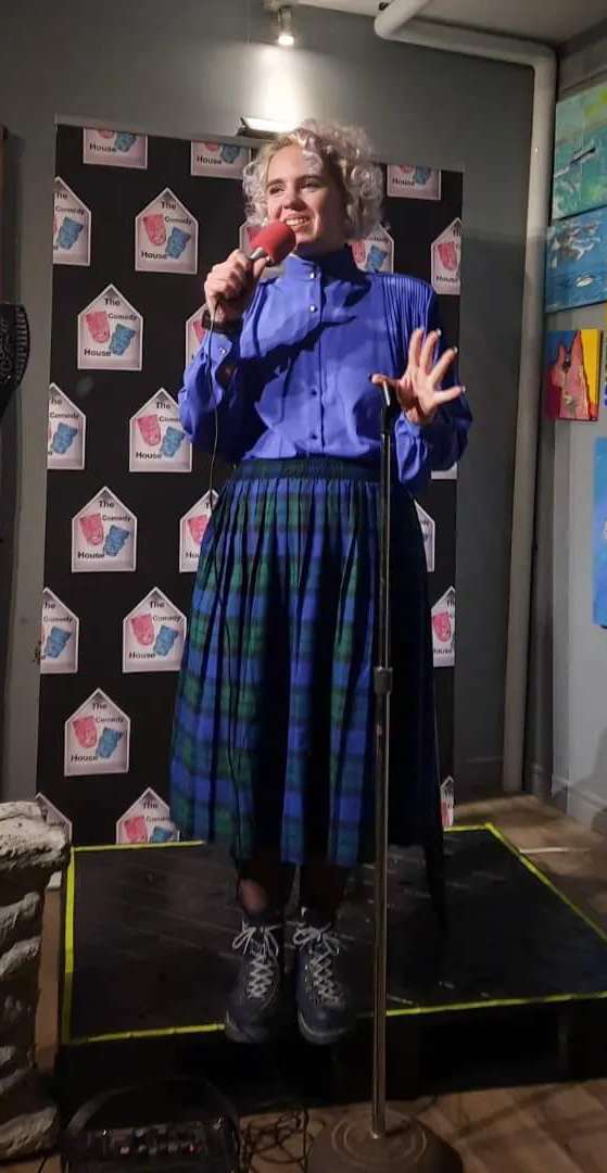 woman on a small stage talking into a microphone